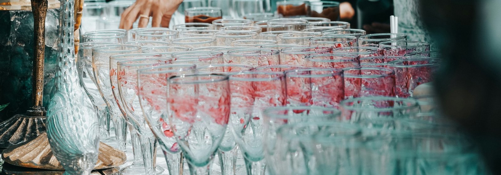 Rows of wine glasses being filled at an evening reception
